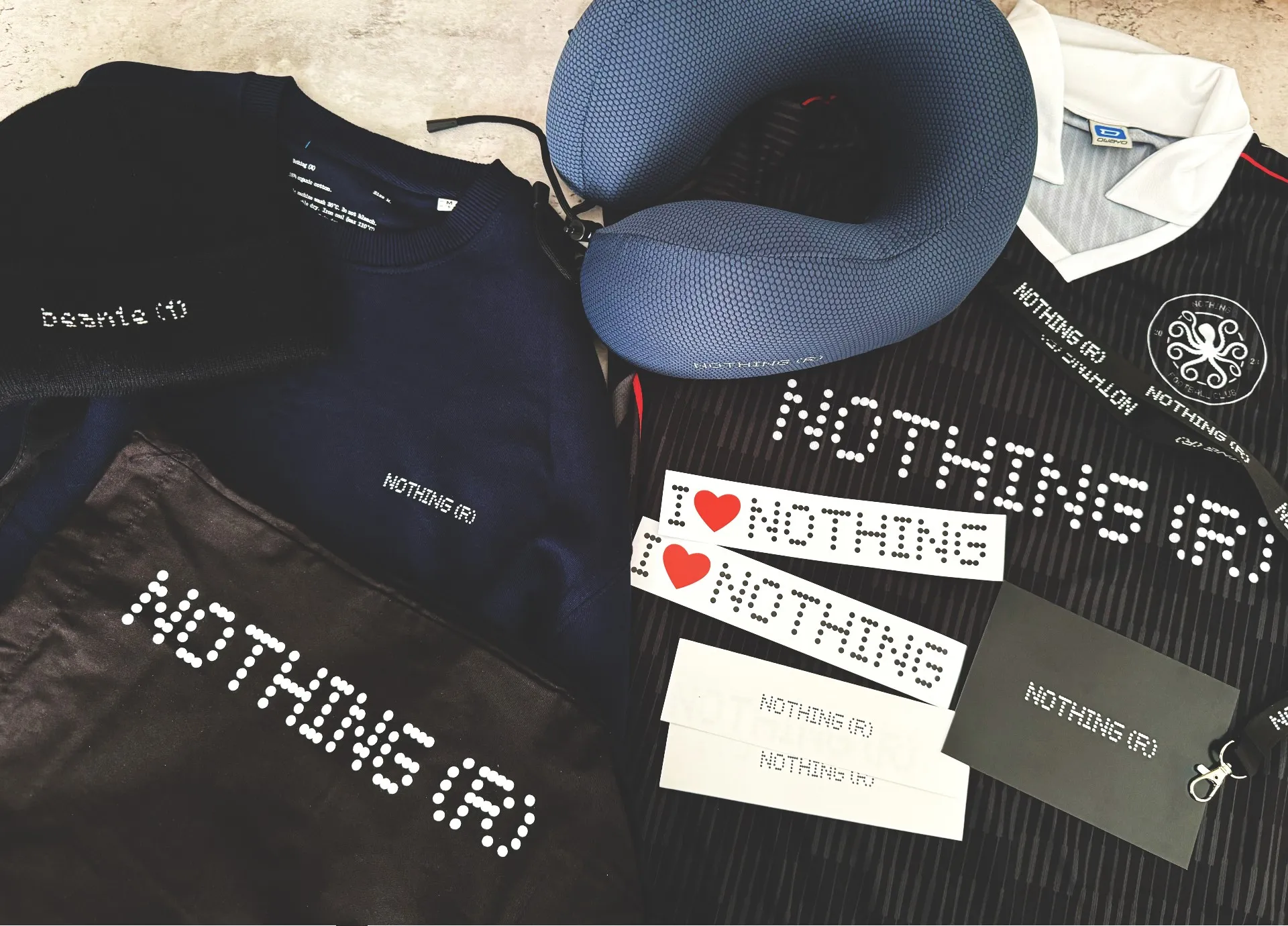 A picture of Nothing merchandise: Beanie (1), a jumper, neck pillow, football shirt, lanyard, stickers and tote bag A picture of Nothing merchandise: Beanie (1), a jumper, neck pillow, football shirt, lanyard, stickers and tote bag